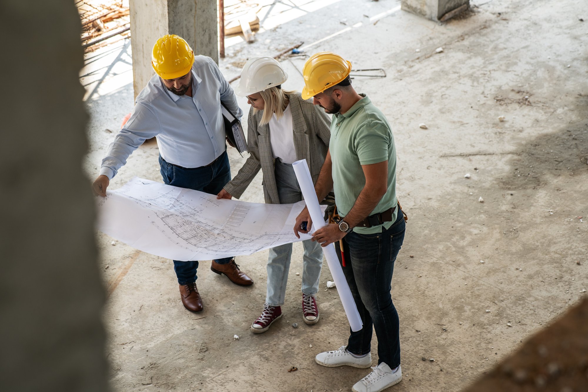 A female architect and construction manager work together on-site, discussing blueprints and coordinating to bring their project to life