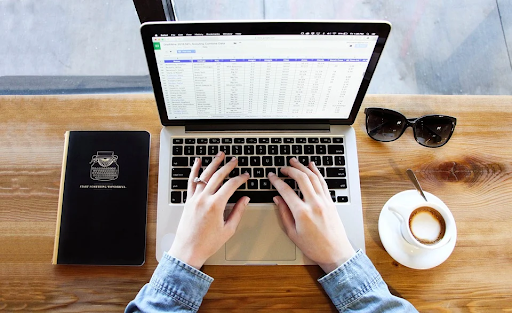 An analyst using her laptop to enter data into a spreadsheet